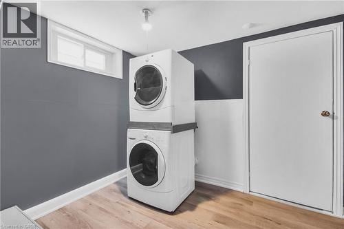 Stackable laundry appliances with a wood-finish floor and white trim - 185 Burlington Street, London, ON - Indoor Photo Showing Laundry Room