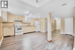 Kitchen area featuring wood-finish flooring, light-toned cabinetry, and white appliances - 
