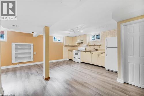 Spacious room featuring wood-finish flooring, built-in shelving, and a kitchen area with cabinetry, a sink, and appliances - 185 Burlington Street, London, ON - Indoor Photo Showing Kitchen