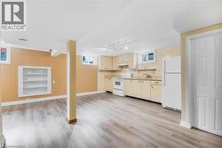 Spacious room featuring wood-finish flooring, built-in shelving, and a kitchen area with cabinetry, a sink, and appliances - 