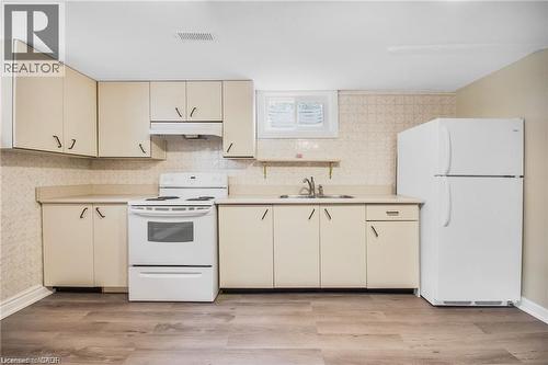 Kitchen featuring light wood-finish cabinetry, white appliances, durable countertops, and wood-finish flooring - 185 Burlington Street, London, ON - Indoor Photo Showing Kitchen With Double Sink