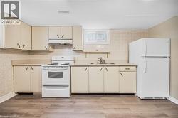 Kitchen featuring light wood-finish cabinetry, white appliances, durable countertops, and wood-finish flooring - 