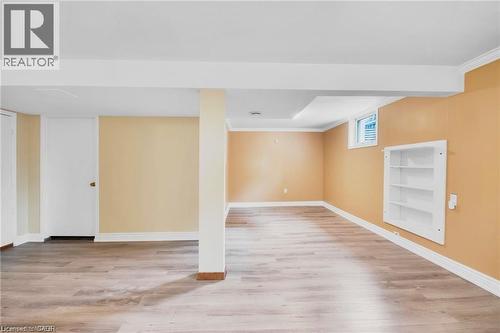 Spacious lower level featuring wood-finish flooring, recessed lighting, an egress window, and built-in shelving - 185 Burlington Street, London, ON - Indoor Photo Showing Other Room