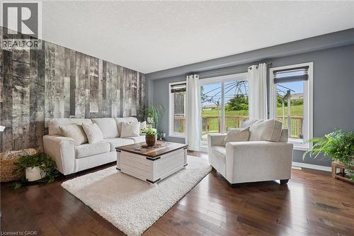Hardwood-style flooring, a wood-panel accent wall, and a sliding glass door with transom window - 308 Parkvale Drive, Kitchener, ON - Indoor Photo Showing Living Room