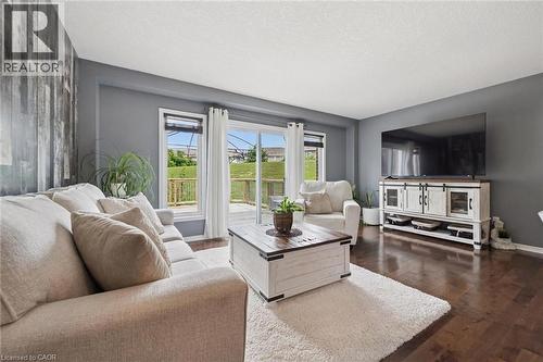 Dark wood-finish flooring, accent wall with wood paneling, sliding glass door with deck access, built-in entertainment console, and neutral wall paint - 308 Parkvale Drive, Kitchener, ON - Indoor Photo Showing Living Room