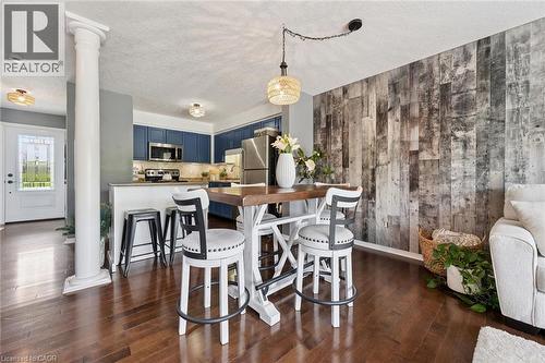 Wood-finish flooring throughout, featuring a kitchen with blue cabinetry and stainless steel appliances - 308 Parkvale Drive, Kitchener, ON - Indoor Photo Showing Dining Room