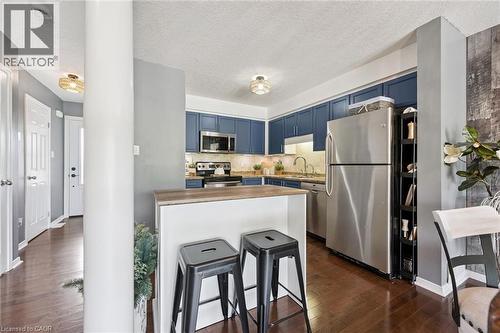 Kitchen featuring blue cabinetry, stainless steel appliances, a wood-finish breakfast bar, and wood-finish flooring - 308 Parkvale Drive, Kitchener, ON - Indoor Photo Showing Kitchen
