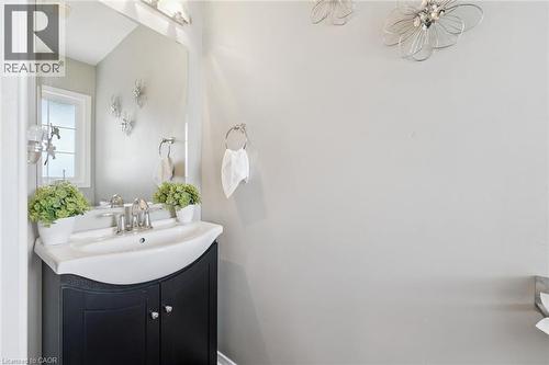 Black vanity with a white integrated sink, chrome faucet, and rectangular wall mirror - 308 Parkvale Drive, Kitchener, ON - Indoor Photo Showing Bathroom