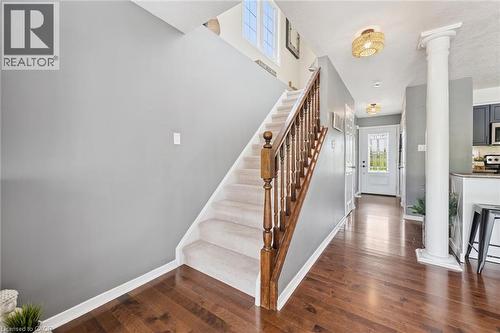 Hardwood-finish flooring, carpeted staircase with wood railing, decorative column, transom window, and built-in lighting - 308 Parkvale Drive, Kitchener, ON - Indoor Photo Showing Other Room With Fireplace