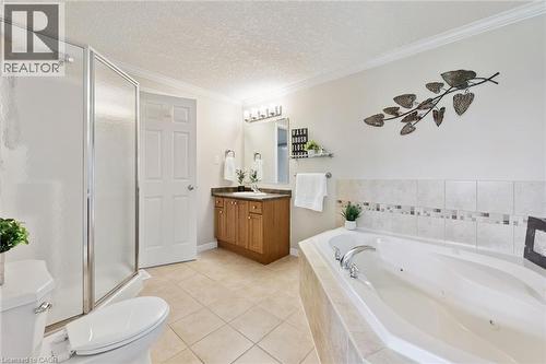 Tiled flooring, built-in soaking tub, wood-finish vanity with countertop, framed mirror, and glass-enclosed shower - 308 Parkvale Drive, Kitchener, ON - Indoor Photo Showing Bathroom