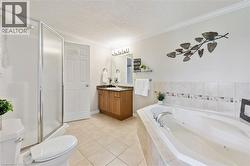 Tiled flooring, built-in soaking tub, wood-finish vanity with countertop, framed mirror, and glass-enclosed shower - 