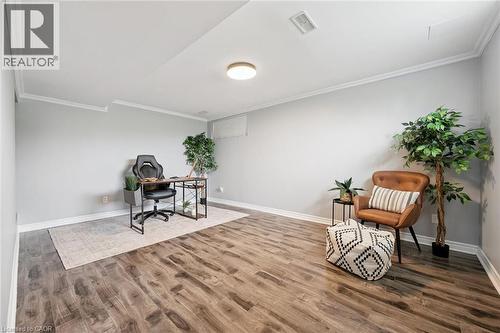 Spacious room featuring wood-finish flooring, light gray walls, and white crown molding - 308 Parkvale Drive, Kitchener, ON - Indoor