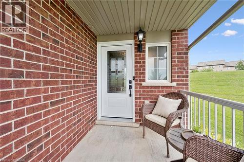 Brick exterior wall, covered concrete porch, white entry door with decorative glass, white-framed window, and exterior wall lantern - 308 Parkvale Drive, Kitchener, ON - Outdoor With Exterior