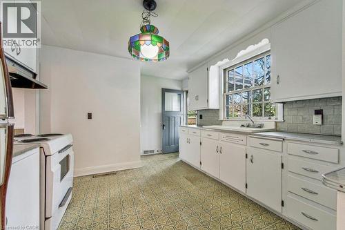 Kitchen featuring patterned flooring, white cabinetry, subway tile backsplash, and a stained glass ceiling fixture - 321 Highland Park, Cambridge, ON 
