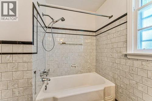 Bathtub with white subway tile surround, integrated shower, and transom window - 321 Highland Park, Cambridge, ON 