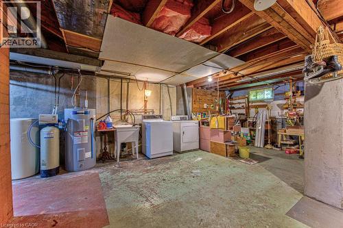Basement utility area featuring exposed wood beam ceiling, concrete flooring, washer, dryer, and a utility sink - 321 Highland Park, Cambridge, ON 