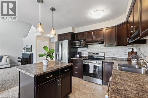 Kitchen featuring dark wood-finish cabinetry, stainless steel appliances, a tile backsplash, composite countertops, and a kitchen island with pendant lighting - 783 Frontenac Crescent, Woodstock, ON - Indoor Photo Showing Kitchen With Double Sink With Upgraded Kitchen