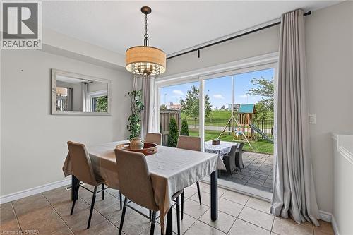 Dining area featuring a drum pendant light fixture, ceramic tile flooring, and a sliding glass door - 783 Frontenac Crescent, Woodstock, ON - Indoor Photo Showing Dining Room