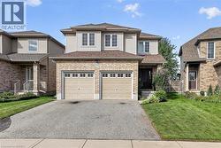 Stone and siding exterior with a two-car garage, front entry, and mature landscaping - 