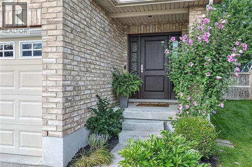 Brick facade with a dark wood-finish entry door, concrete steps, and integrated landscaping - 783 Frontenac Crescent, Woodstock, ON - Outdoor