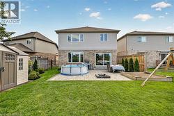 Expansive rear yard featuring a manicured lawn, paver patio, integrated fire pit, and a storage shed - 