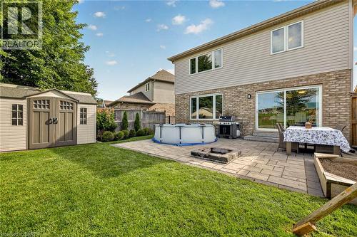 Expansive backyard featuring a manicured lawn, a large paver patio, a built-in stone fire pit, and a storage shed - 783 Frontenac Crescent, Woodstock, ON - Outdoor With Above Ground Pool With Exterior