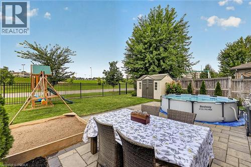 Paved patio area, manicured lawn, secure perimeter fencing, and mature trees - 783 Frontenac Crescent, Woodstock, ON - Outdoor With Above Ground Pool With Deck Patio Veranda