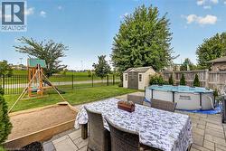 Paved patio area, manicured lawn, secure perimeter fencing, and mature trees - 
