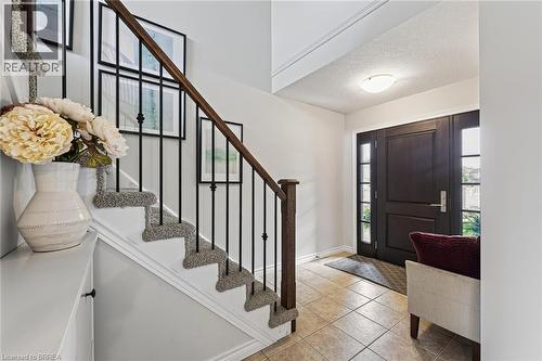 Warm tiled flooring with a dark wood-finish entry door featuring sidelight windows - 783 Frontenac Crescent, Woodstock, ON - Indoor Photo Showing Other Room