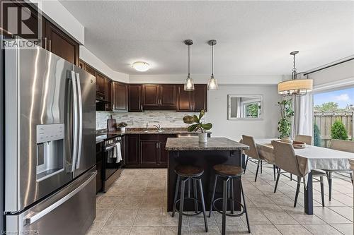 Kitchen featuring dark wood cabinetry, stainless steel appliances, a center island with pendant lighting, and tile flooring - 783 Frontenac Crescent, Woodstock, ON - Indoor