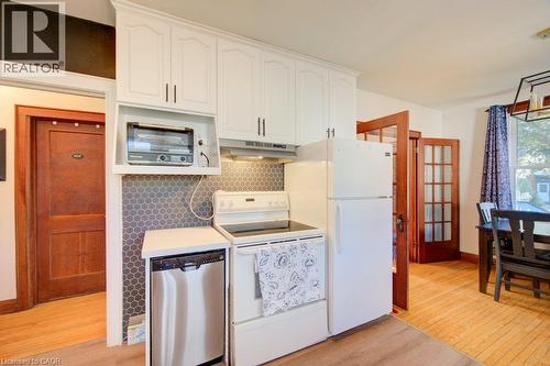 White cabinetry, stainless steel dishwasher, hexagonal tile backsplash, wood-finish flooring, and French doors - 97 Francis Street, Cambridge, ON - Indoor Photo Showing Kitchen