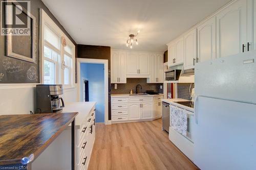 Kitchen featuring white cabinetry, wood-finish flooring, a mosaic tile backsplash, and white appliances - 97 Francis Street, Cambridge, ON - Indoor Photo Showing Kitchen