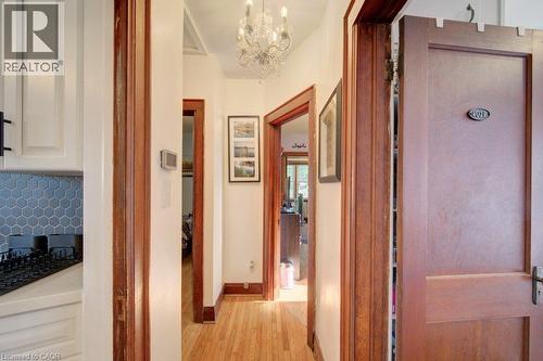 Hardwood flooring throughout, a decorative chandelier, white cabinetry with dark hardware, and a hexagonal tile backsplash - 97 Francis Street, Cambridge, ON - Indoor Photo Showing Other Room