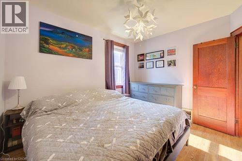 Hardwood flooring, light purple wall paint, wood-paneled door, modern ceiling fixture, and a window with purple drapes - 97 Francis Street, Cambridge, ON - Indoor Photo Showing Bedroom