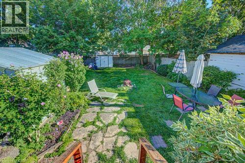 Expansive backyard featuring a lush lawn, stone pathway, established garden beds, and mature trees - 97 Francis Street, Cambridge, ON - Outdoor