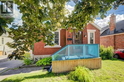 Brick exterior with white trim, wood front porch with blue railing, and a side driveway - 97 Francis Street, Cambridge, ON - Outdoor