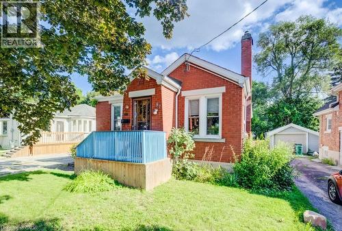 Red brick exterior with white trim, a front porch with blue railings, a detached garage, and a paved driveway - 97 Francis Street, Cambridge, ON - Outdoor