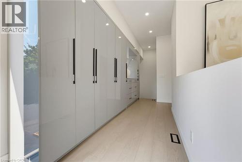 Streamlined hallway featuring extensive built-in cabinetry with matte black hardware, recessed lighting, and light wood-finish flooring - 282 Robina Road, Ancaster, ON - Indoor Photo Showing Other Room