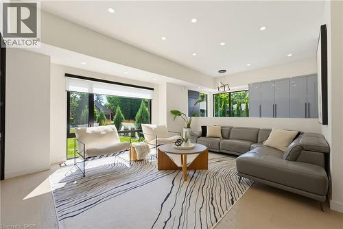 Spacious living area featuring large windows, recessed lighting, light wood-finish flooring, and built-in gray cabinetry - 282 Robina Road, Ancaster, ON - Indoor Photo Showing Living Room