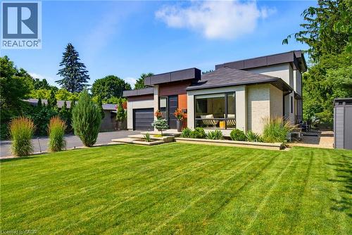 Modern architectural residence featuring a two-car garage, expansive lawn, and mature landscaping - 282 Robina Road, Ancaster, ON - Outdoor