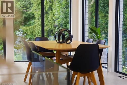 Dining area featuring expansive floor-to-ceiling windows, wood-finish flooring, and a contemporary light wood table - 282 Robina Road, Ancaster, ON - Indoor Photo Showing Dining Room