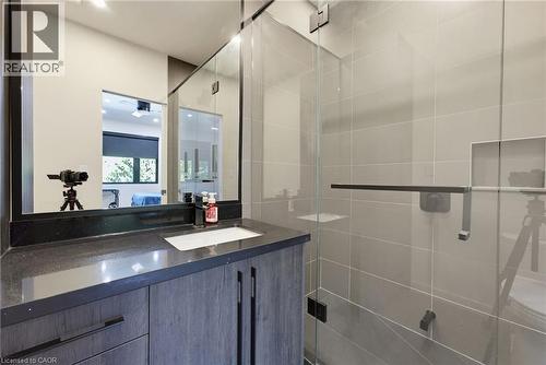 Contemporary bathroom featuring a dark wood-finish vanity with a single basin sink, a dark countertop, and a sleek rectangular mirror - 282 Robina Road, Ancaster, ON - Indoor Photo Showing Bathroom