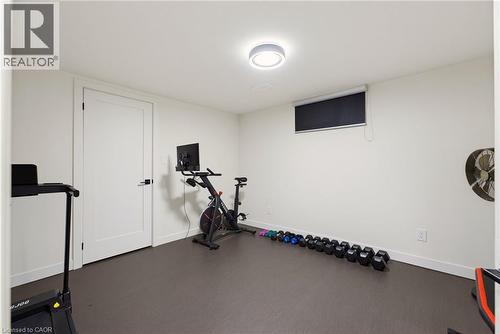 Spacious room with durable dark gray flooring, a single window with a roller shade, recessed lighting, and a white interior door with black hardware - 282 Robina Road, Ancaster, ON - Indoor Photo Showing Gym Room