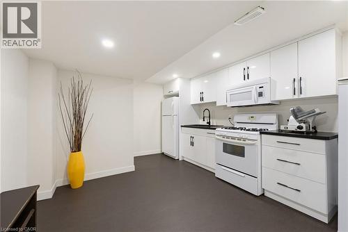 Kitchen area featuring white cabinetry, dark countertops, a white gas range, and a white over-the-range microwave - 282 Robina Road, Ancaster, ON - Indoor Photo Showing Kitchen