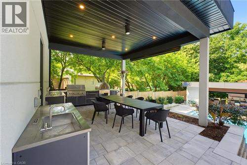 Expansive covered patio featuring an outdoor kitchen with built-in grill and pizza oven, recessed lighting, and paver flooring - 282 Robina Road, Ancaster, ON - Outdoor With Deck Patio Veranda With Exterior