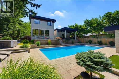 Contemporary exterior featuring a rectangular in-ground pool, expansive paver patio, a built-in hot tub, and a covered outdoor living area - 282 Robina Road, Ancaster, ON - Outdoor With In Ground Pool With Backyard
