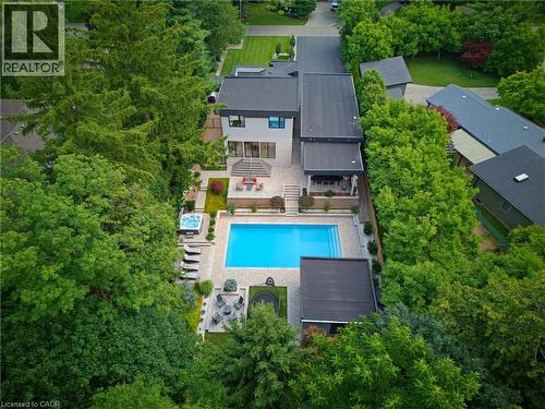 Modern residence featuring a rectangular swimming pool with integrated steps, an adjacent hot tub, and an expansive paved patio - 282 Robina Road, Ancaster, ON - Outdoor With In Ground Pool