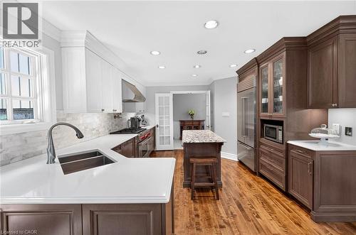 Gourmet kitchen with wood-finish flooring, recessed lighting, white and wood-finish cabinetry, stainless steel appliances, and a central island with a stone-finish countertop - 11 Christman Court, Markham, ON - Indoor Photo Showing Kitchen With Double Sink With Upgraded Kitchen
