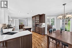 Hardwood flooring, recessed lighting, white perimeter cabinetry, dark wood island with light countertop, and a built-in refrigerator - 