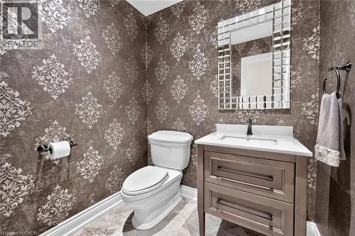 Damask-patterned walls with a wood-finish vanity, white countertop, and a tiled mirror frame - 11 Christman Court, Markham, ON - Indoor Photo Showing Bathroom